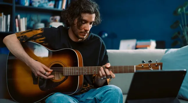 A guitarist tuning their instrument with the GuitarTuna app